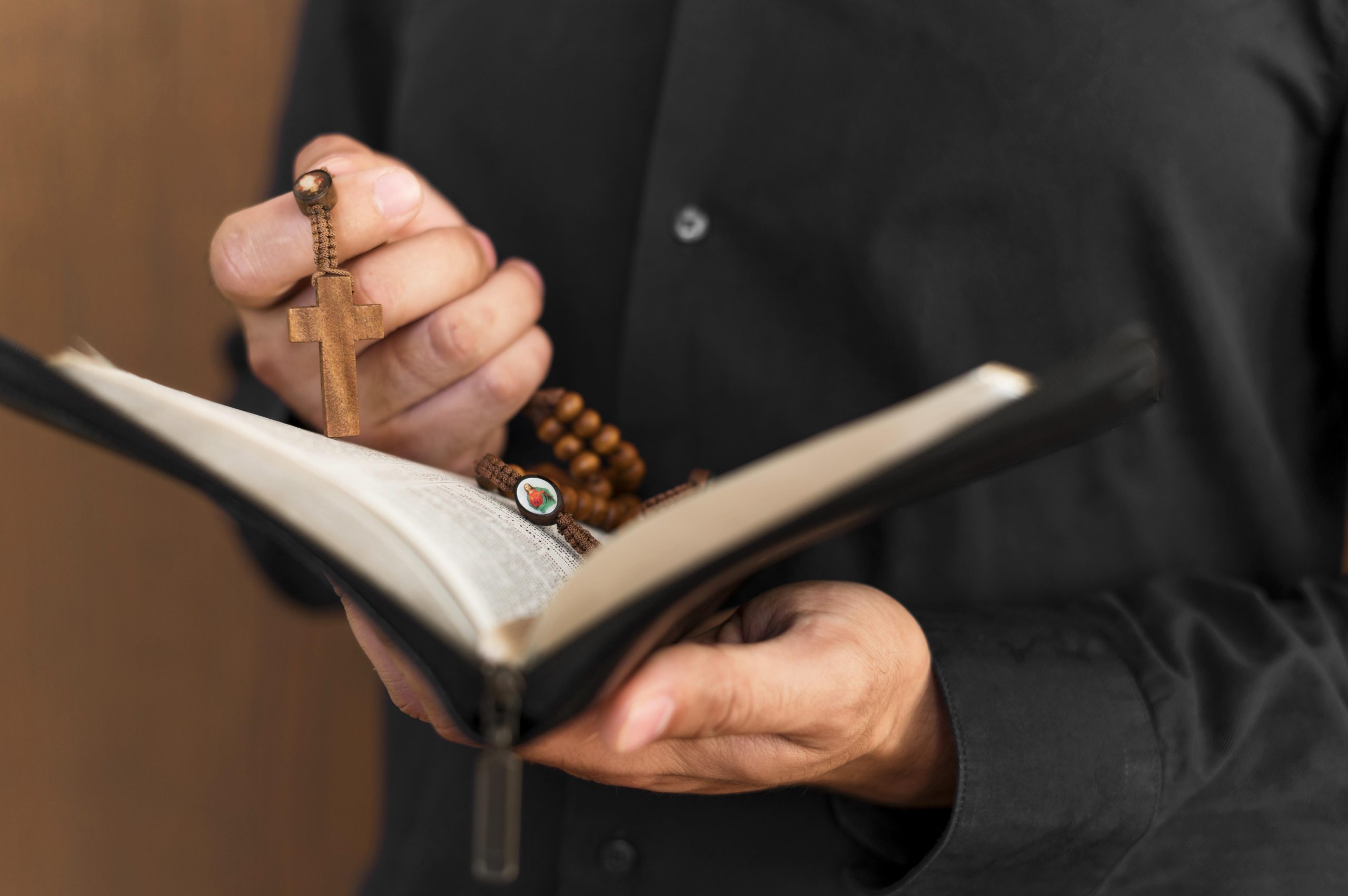 front-view-person-holding-holy-book-rosary