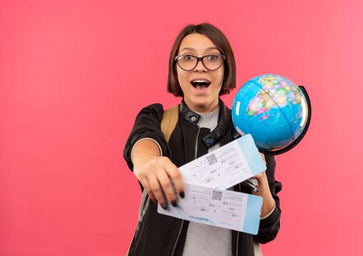 impressed-young-student-girl-wearing-glasses-back-bag-stretching-out-airplane-tickets-holding-globe-isolated-pink_141793-83871