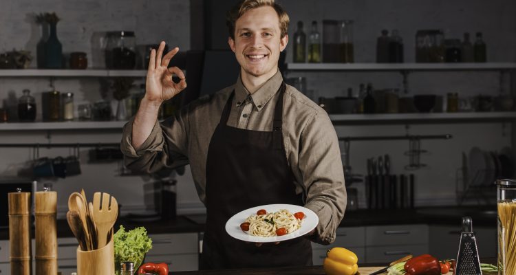 mid-shot-chef-holding-plate-with-pasta-making-ok-sign